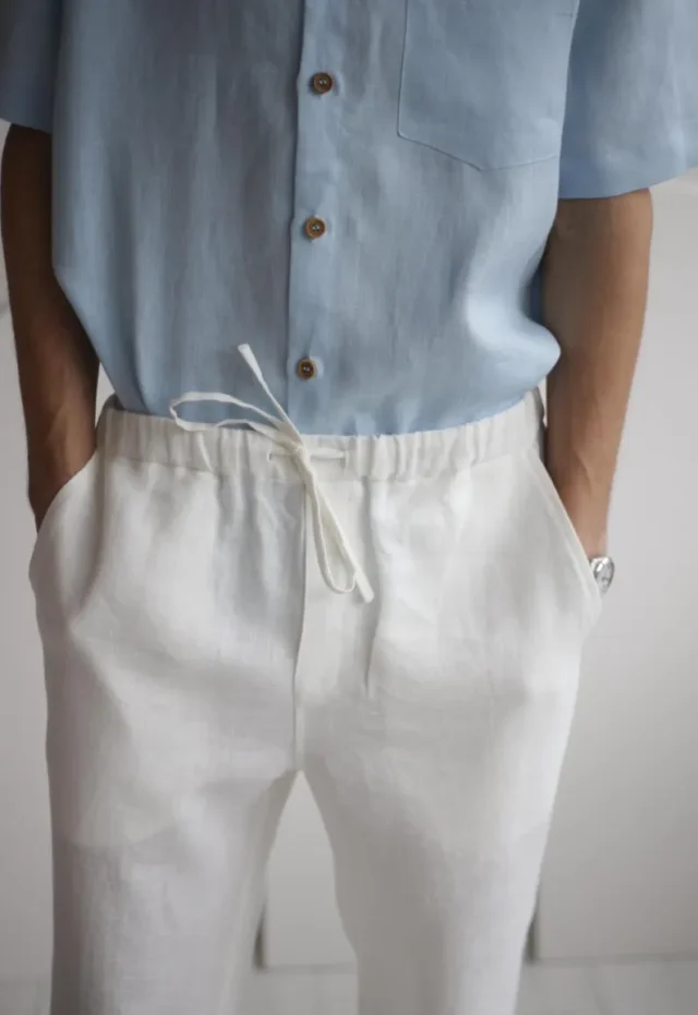 Man wearing FLORIDA white linen pants, featuring a comfortable elastic waistband and pockets, styled for a relaxed yet smart summer look.