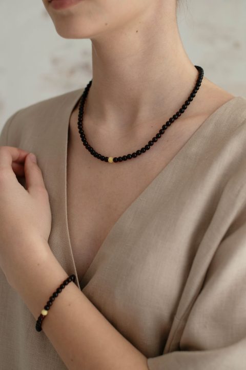 Woman wearing dark Baltic amber necklace with beige linen wrap blouse